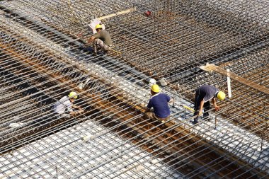 İnşaat alanında beton döşeme için takviye metal iskeleti yapan işçiler