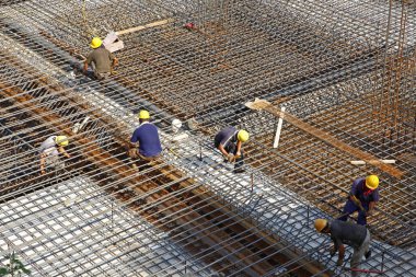 İnşaat alanında beton döşeme için takviye metal iskeleti yapan işçiler