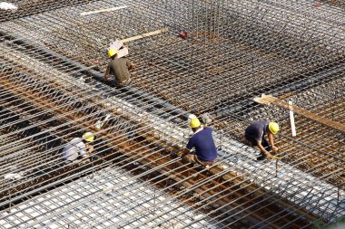 İnşaat alanında beton döşeme için takviye metal iskeleti yapan işçiler