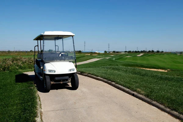 绿色高尔夫球场的白色高尔夫球车 — 图库照片