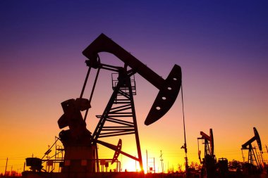 Petrol sahası sahnesi, ışın pompalama ünitesinin siluette olduğu gece. 
