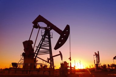 Petrol sahası sahnesi, ışın pompalama ünitesinin siluette olduğu gece. 