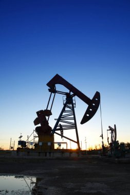 Petrol sahası sahnesi, ışın pompalama ünitesinin siluette olduğu gece. 