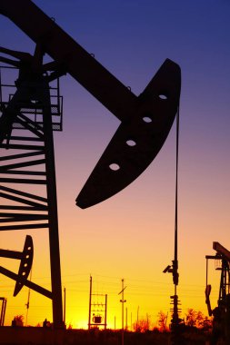 Petrol sahası sahnesi, ışın pompalama ünitesinin siluette olduğu gece. 