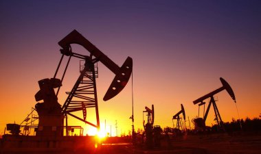 Petrol sahası sahnesi, ışın pompalama ünitesinin siluette olduğu gece. 