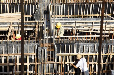 İnşaat alanındaki işçiler beton döşeme için takviye metal iskeleti yapıyorlar