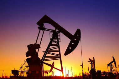 Petrol sahası sahnesi, ışın pompalama ünitesinin siluette olduğu gece. 