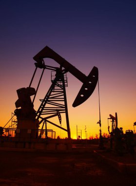 Petrol sahası sahnesi, ışın pompalama ünitesinin siluette olduğu gece. 