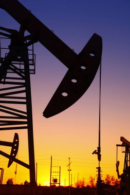 Petrol sahası sahnesi, ışın pompalama ünitesinin siluette olduğu gece. 