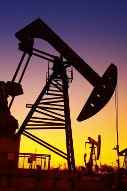 Petrol sahası sahnesi, ışın pompalama ünitesinin siluette olduğu gece. 