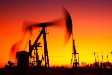 Petrol sahası sahnesi, ışın pompalama ünitesinin siluette olduğu gece. 