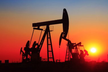 Petrol sahası sahnesi, ışın pompalama ünitesinin siluette olduğu gece. 
