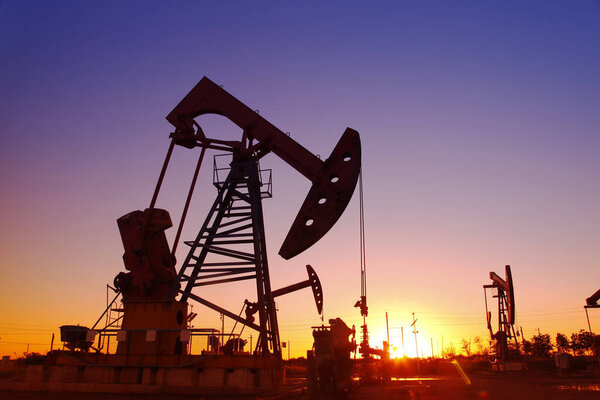 Oil field scene, the evening of beam pumping unit in silhouette 