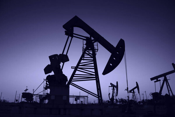 Oil field scene, the evening of beam pumping unit in silhouette 