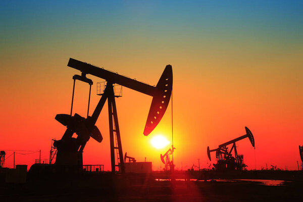 Oil field scene, the evening of beam pumping unit in silhouette 