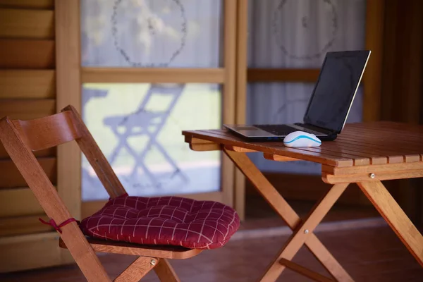 Nomad werk concept afbeelding met computer op houten tafel en zonlicht, wazig bomen van natuur park achtergrond en zomer seizoen — Stockfoto