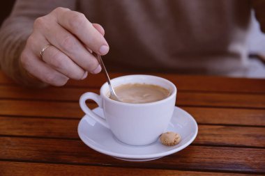  Detay zaman, açık bir fincan espresso kahve karıştırma bir kaşık tutan adamın elini rahatla