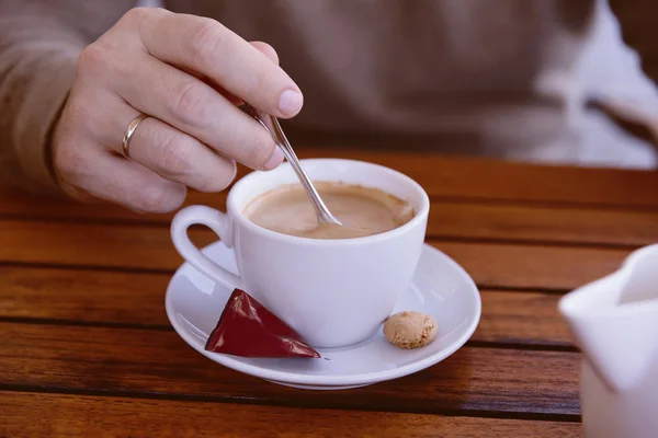 Detail of man\'s hand holding a spoon stirring a cup of espresso coffee,relax time,outdoor