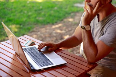 Ahşap masa evde tablet pc dizüstü bilgisayar üzerinde çalışan bir iş adamı. Evde, ev ofis kavramı çalışma. Dizüstü bilgisayarda çalışan adam. Tatil sırasında çalışan adam. Adam açık havada tatilde çalışma dizüstü bilgisayar ile