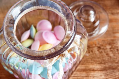 Kavanoz masada ahşap arka plan üzerinde renkli şekerler. Eski ahşap arka plan üzerinde renkli şekerler bir depodan dökülüp, kavanoz.