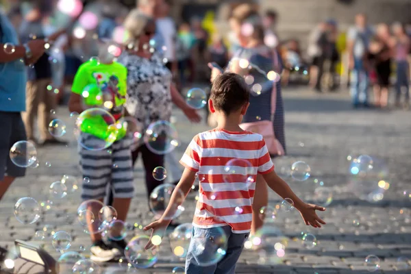 7 years old boy in red t-shirt blow soap bubble in the city. Childhood happy conception — Stock Photo, Image