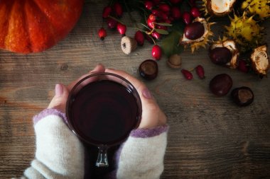 Kuşburnu çay çay ve rose hips ve kestane oluşan tutan eller, ahşap arka plan üzerinde yaprak. Mevsimlik, vitamin içeceği. Sonbahar arka plan.