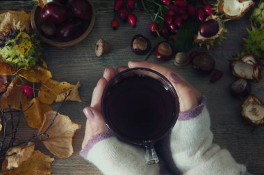 Kuşburnu çay çay ve rose hips ve kestane oluşan tutan eller, ahşap arka plan üzerinde yaprak. Mevsimlik, vitamin içeceği. Sonbahar arka plan.