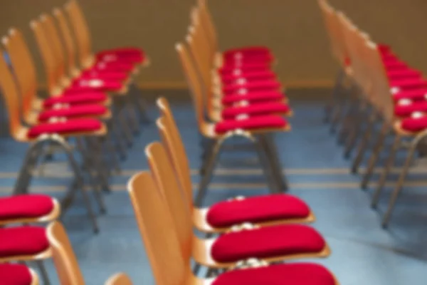 Blurred rows of empty wooden chairs in a large assembly hall.Empty chairs in conference hall.Interior meeting room.