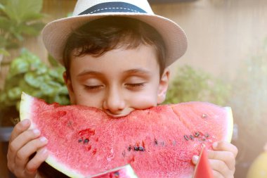 Yakışıklı çocuk yemek sağlıklı organik yiyecek, panama Kupası ile karpuz. doğa arka plan, güneşli ışıklar