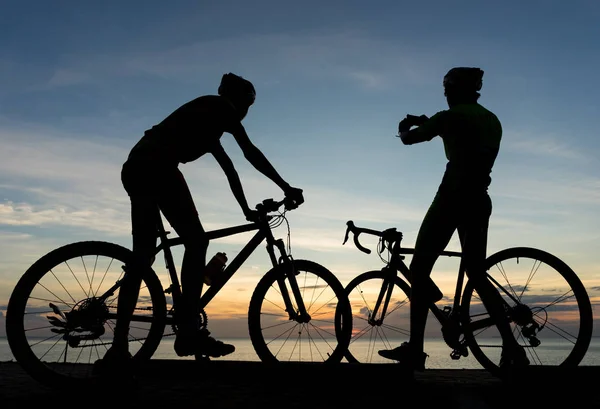 Siluety cyklistů na kole v oceánu v západu slunce sc — Stock fotografie