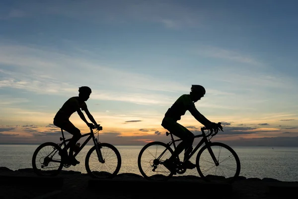 Silhuetas de ciclistas de bicicleta no oceano ao pôr do sol sc — Fotografia de Stock
