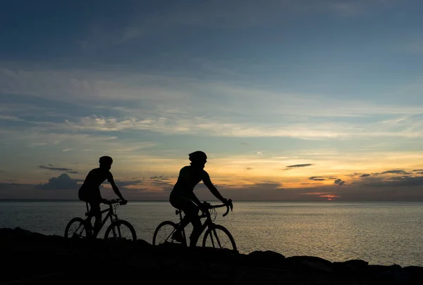 Silhouetten von Radfahrern am Meer im Sonnenuntergang sc — Stockfoto