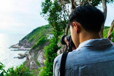 Doğada fotoğraf çeken yakışıklı Asyalı fotoğrafçı..