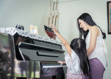 Mutlu bir anne ve kızı birlikte siyah bir büyük boya oynuyorlar.