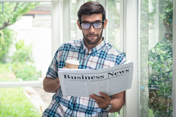 Young casual businessman reading business news in the morning at