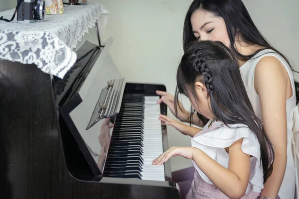 Lycklig mor och dotter spelar en svart grand paino tillsammans jag — Stockfoto