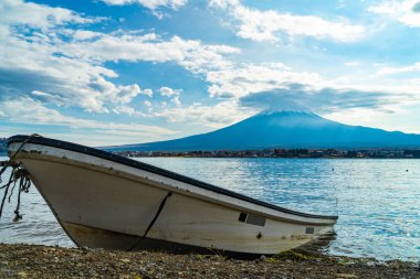 Bulutlu bir günde Fuji Dağı 'nda tekne parkında. Suda yansıması var. Kawaguchiko göl bölgesi - Yamanashi, Japonya.