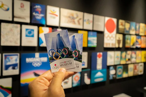 TOKYO, JAPAN - marraskuu 26, 2019: Käsiliput aiempien olympialaisten muurilla ja Japanin olympialaisten 2020 julisteella Japanin olympiamuseossa . — kuvapankkivalokuva