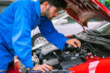 Tamirciler mavi takım elbiseli arabayı kontrol edip tamir ediyorlar. Otomobil servisi kavramları