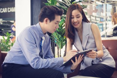 Satıcı, araba galerisinden yeni bir araba aldıktan sonra mutlu Asyalı genç kıza sözleşmenin detaylarını gösteriyor. Film tonu etkin.