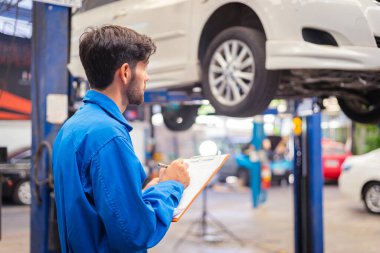 Tamirci arabayı kontrol ediyor ve kağıda not alıyor. Otomobil servisi kavramları