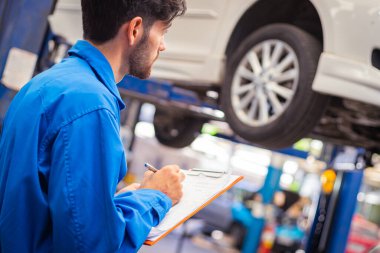 Tamirci arabayı kontrol ediyor ve kağıda not alıyor. Otomobil servisi kavramları
