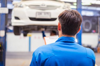 Tamirci arabayı kontrol ediyor ve kağıda not alıyor. Otomobil servisi kavramları