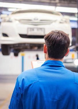 Tamirci arabayı kontrol ediyor ve kağıda not alıyor. Otomobil servisi kavramları