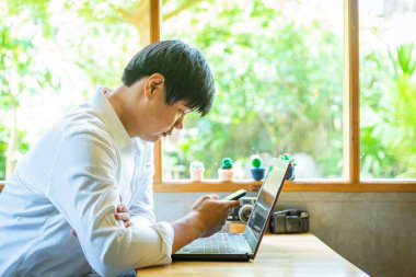 Asyalı işadamı bir kafede akıllı telefon kullanıyor.