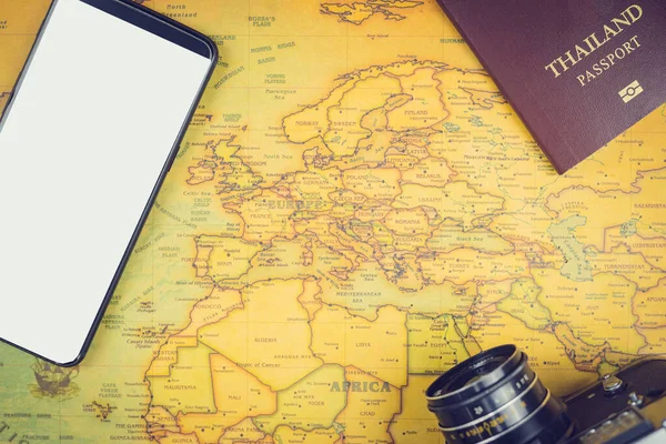 Travel accessories concepts : It's time to go to travel around the world - The image of a world map with essentials accessories - smart phone, passport and camera. Vintage tone style. Top view picture.