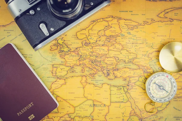 Travel accessories concepts : It\'s time to go to travel around the world - The image of a world map with essentials accessories - passport, compass and camera. Vintage tone style. Top view picture.