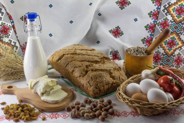 Ekmek, tuzlu peynir, süt, Kuru üzüm, ayçiçeği tohumu, sarımsak, domates, acı biber ve Ukraynalı havlu arka plan üzerinde fındık