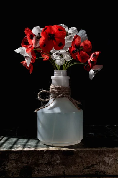 プラスチック ボトルで古い木製のテーブルでケシの花 — ストック写真