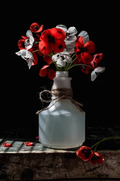 Poppy flowers on an old wooden table in a plastic bottle — Stock Photo, Image